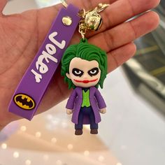 the joker keychain is being held in someone's hand