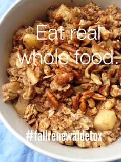 a white bowl filled with granola and nuts on top of a blue table cloth