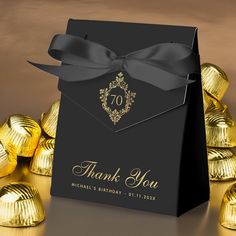 a black box with gold foiled chocolates and a ribbon tied around the top