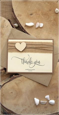 a thank card with a heart on it sitting next to some wood slices and shells