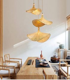 three lights hanging from the ceiling above a table with chairs and other items on it