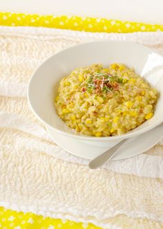 a white bowl filled with food sitting on top of a yellow and white table cloth