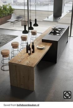 a modern kitchen with an island table and stools in front of the countertop