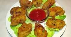 a white plate topped with lettuce covered in chicken nuggies and ketchup