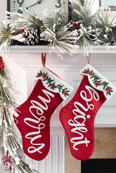 two stockings hanging from a mantel decorated with holly and pine cones that say merry christmas