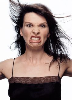 a woman with her hair blowing in the wind while wearing a black top and brown bra