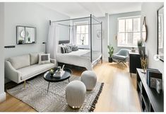 a living room with white furniture and wood flooring, including a four poster bed