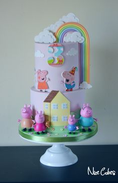 a three tiered cake with peppa pig figures on the top and rainbow in the background