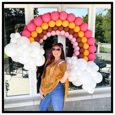 a woman standing in front of a doorway with balloons on the door and an arch