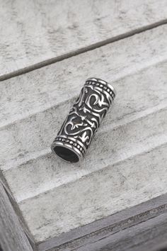 an ornate silver ring sitting on top of a wooden table next to a brick wall