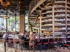 people sitting at tables in a restaurant with lots of bottles on the walls