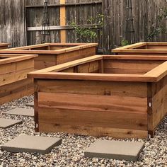 several wooden planters are lined up on the gravel