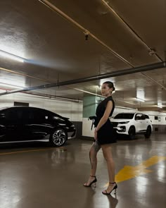 a woman standing in a parking garage next to two cars