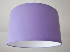 a purple lampshade hanging from a ceiling with a white light fixture in the background