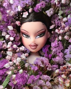 a close up of a doll surrounded by purple and white flowers with her eyes closed