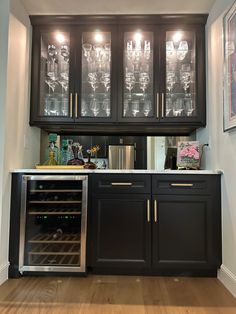 a kitchen with black cabinets and wine glasses on the glass doored cabinet above it