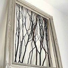 a mirror with some branches in it on the wall next to a fireplace mantel