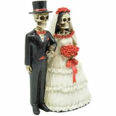 a skeleton bride and groom figurine standing next to each other on a white background