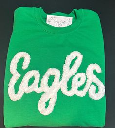 Show your school spirit in this cute sweatshirt. Comfort, casual and loose fitting, made on 50/50 cotton/poly blend shirts.  Embroidered chenille yarn, Eagles sweatshirt.  Show your school spirit in this cute sweatshirt. Comfort, casual and loose fitting, made on 80/20 cotton/poly blend shirts.  Please message us if you have a custom color request and we will create a separate listing for custom requests.  You can follow us at the below link for chances to win giveaways and to see all of our latest creations.  https://www.facebook.com/groups/710060383256657/?ref=share&mibextid=S66gvF You can follow us at the below link for chances to win giveaways and to see all of our latest creations. Collegiate Long Sleeve Cotton Sweatshirt, Collegiate Crew Top In French Terry, College Cotton Sweater With Embroidered Graphics, Cotton College Sweater With Embroidered Graphics, Sporty Cotton Sweater With Embroidered Graphics, Varsity Fleece Top For Fan Gear, Pre-shrunk Crew Neck Sweatshirt For School Spirit, Green Crew Neck Sweatshirt For Sports Season, Cotton Crew Sweats For College