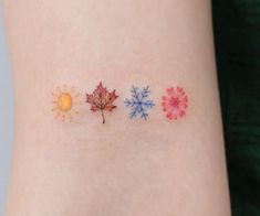 a small tattoo on the side of a woman's arm with four different colored leaves