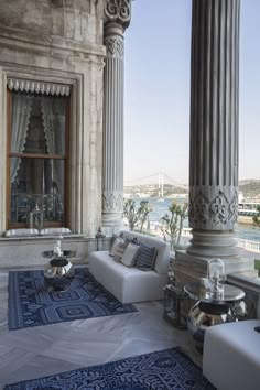 a living room filled with furniture next to tall pillars