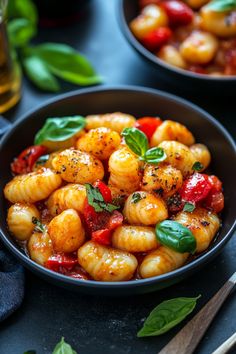 Gnocchi with cherry tomatoes, basil, and cracked black pepper in a black bowl on a dark table. Gnocchi Bolognese Recipe, Gnocchi Bolognese