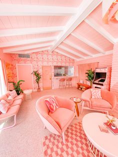 a living room filled with pink furniture and walls covered in floral wallpaper, along with a piano