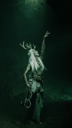 a woman dressed as an elf with horns and deer antlers on her head in the dark