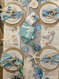 the table is set with blue and white plates, napkins, and seashells