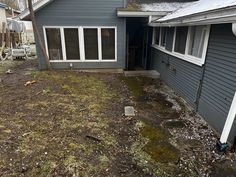 a blue house with grass and dirt on the ground