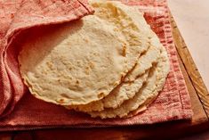 three tortillas on a red cloth next to a wooden cutting board