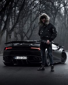 a man standing next to a black sports car