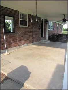 an empty porch in front of a brick house