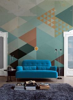 a blue couch sitting in front of a wall with geometric designs on it's walls