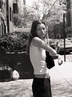 a young woman is standing on the sidewalk