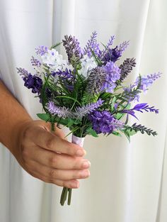 a person holding a bouquet of purple and white flowers in their left hand while wearing a white shirt