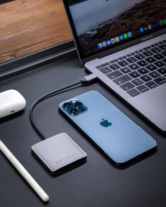 an open laptop computer sitting on top of a desk next to a phone and charger