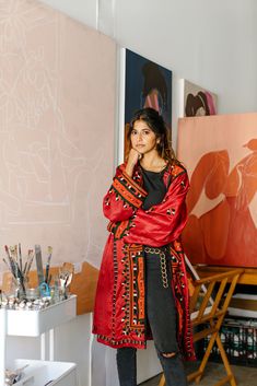 a woman standing in front of an art work with her hand on her chin and looking at the camera