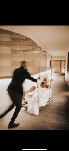 a man and woman in wedding attire running on a bed with their arms around each other