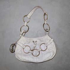 Gorgeous white leather YSL Saharienne bag from Tom Ford's era. Gold hardware. Good vintage condition but some dullness and marks to the leather, as pictured. Most notably the black marks from the rings rubbing on the leather. Nothing super bad.  MEASUREMENTS: Width: approx. 29cm Height: approx. 19cm Depth: approx. 5.5cm Handle Drop: approx. 26cm Vintage White Bags With Gold-tone Hardware, White Leather Bags With Brass Hardware, Vintage White Leather Shoulder Bag, White Vintage Leather Shoulder Bag, The Rings, Tom Ford, White Leather, Gold Hardware, Purses And Handbags