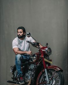 a man sitting on top of a red motorcycle