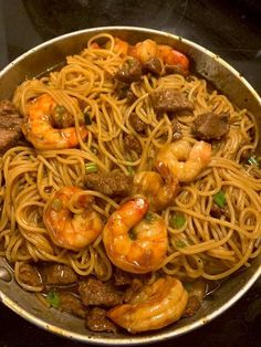 a pan filled with pasta and shrimp on top of a stove