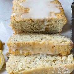 two slices of lemon poppy seed bread with glaze on top and sliced lemons in the background