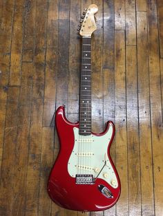 a red electric guitar sitting on top of a wooden floor