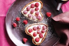 two pieces of pie on a plate with raspberries and powder sprinkles