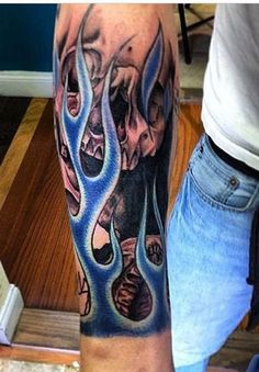 a man's arm with a skull and flames tattoo on it