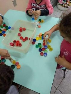 three children are sitting at a table playing with buttons