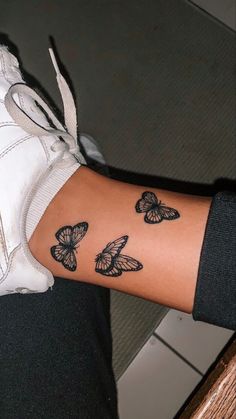 a woman's arm with black butterflies on the left side of her wrist and right hand