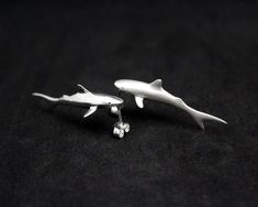 Sharks, such beautiful, strong creatures. They represent strength, intuition, dominance, the deep blue ocean and its mysteries. If you are a fan of the jaws this beautiful shark will fit in your taste like a ... shark -----Details---- A shark earrings pair from solid sterling silver hand carved using the lost wax method. Size: 40mm/1.57 inch long, 13mm/0,51 width, 8mm/0.31 high. Check out more sea creatures here https://www.etsy.com/shop/jewelsculpts?section_id=13464974&ref=shopsection_leftn Sci Fi Jewelry, Shark Stuff, Pisces Jewelry, Shark Jewelry, Deep Blue Ocean, Shark Pendant, Black Tungsten Wedding Band, Shark Earrings, Shark Necklace