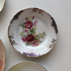 two plates with flowers painted on them are sitting next to each other and one is empty